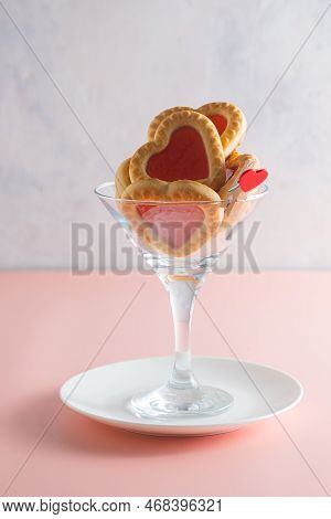 Heart-shaped Cookies With Jam Filling In A Martini Glass On A Pink Plain Background. Valentine's Day