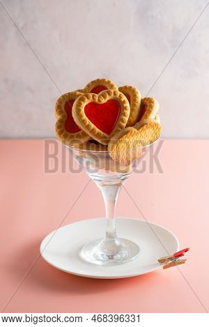 Heart-shaped Cookies With Jam Filling In A Martini Glass On A Pink Plain Background. Valentine's Day