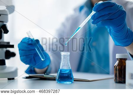 Lab Assistant, A Medical Scientist, A Chemistry Researcher Holds A Glass Tube Through The Blood Samp