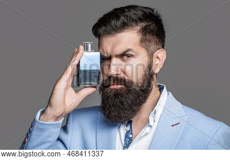 Bearded Man Holding Up Bottle Of Perfume. Fashion Cologne Bottle. Bearded Male Prefers Expensive Fra