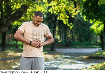 Latin American Runner Sportsman Has Severe Stomach Pain, Man Holding Hand On Side Of Stomach After D
