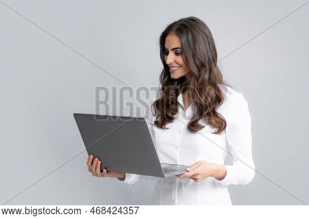 Cheerful Business Woman Standing Over Grey Wall With Laptop Computer. Portrait Of Pretty, Charming, 