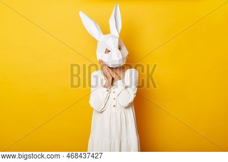 Portrait Of Sleepy Woman Wearing White Dress And Paper Rabbit Mask Standing Isolated Over Yellow Bac
