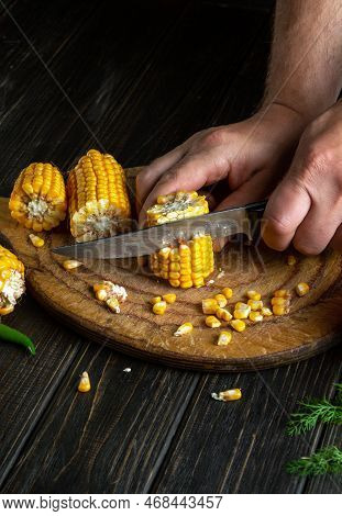The Hands Of The Cook With A Knife Are Cutting Corn. Maize Is An Excellent Dietary Breakfast Or Lunc