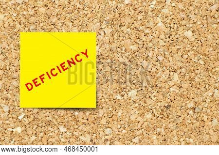 Yellow Note Paper With Word Deficiency On Cork Board Background With Copy Space
