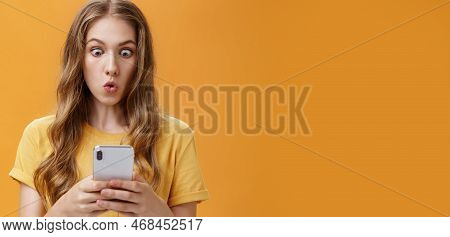 Young Girl Shocked Reading Messages In Friends Smartphone Folding Lips Popping Eyes In Amazement At 