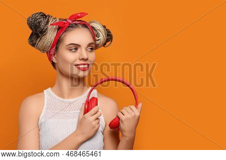 Beautiful Woman With Braided Double Buns And Headphones On Orange Background, Space For Text