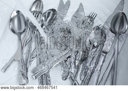 Washing Silver Spoons, Forks And Knives Under Stream Of Water In Kitchen Sink, Top View
