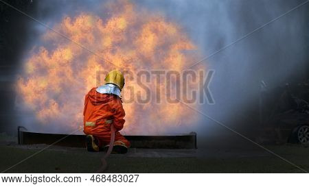 Firefighter Rescue Training In Fire Fighting Extinguisher. Firefighter Fighting With Flame Using Fir