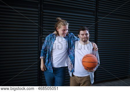 Man With Down Syndrome Playing Basketball Outdoor With His Friend. Concept Of Friendship And Integra