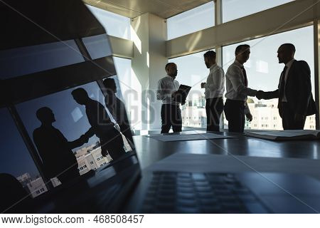 Silhouettes Of People Standing Near A Panoramic Window In A Modern Office. Team Of Young Professiona