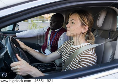 Driving School Concept. A Car Instructor Teaches A Young Woman How To Drive. Teaching The Rules Of T