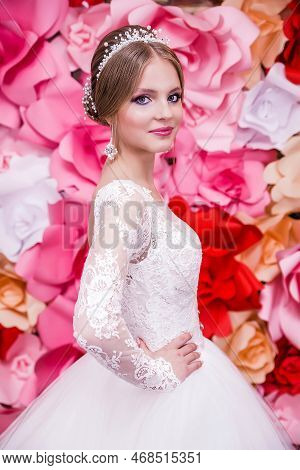 A Girl In A White Wedding Dress With An Open Back, Make-up, A Hairstyle In The Form Of A Bun Poses O