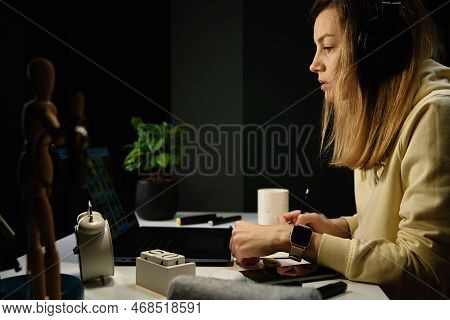 Female Sudent Wearing Headphones Studying At Night Room, Using Laptop. Online Education At Home.