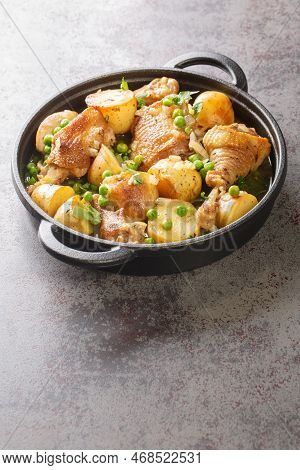 Delicious Pieces Of Chicken Cooked With Potatoes And Green Peas Close-up In A Frying Pan On The Tabl