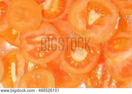 Close-up View Of The Red Tomato Slices In Water Background. Texture Of Cooling Vegeteble Drink With