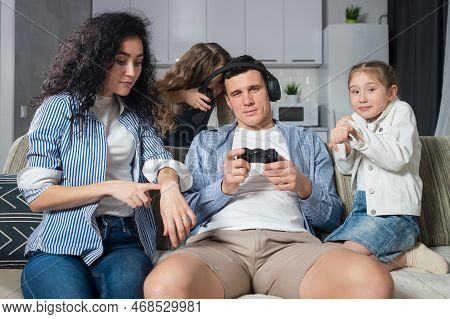 Insistent Daughters And Wife Try To Get Attention Of Father Playing Games With Controller. Man Enjoy