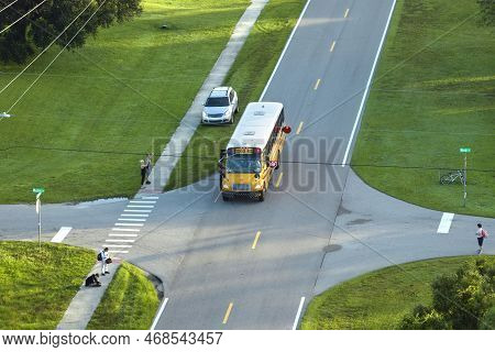 Top View Of Standard American Yellow School Bus Picking Up Kids At Rural Town Street Stop For Their 