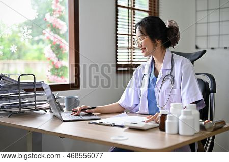 Attractive Asian Female Doctor Using Calculator And Laptop, Estimating Surgery Cost For Her Patient