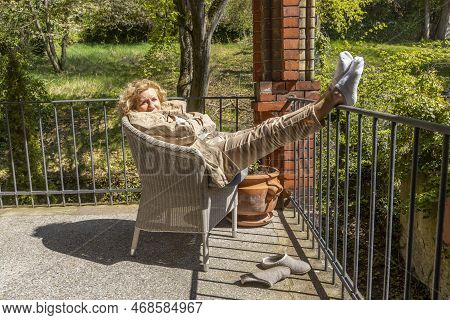 Portrait Of Handsome Smiling Mature Woman Having A Sunbath At The Balcony