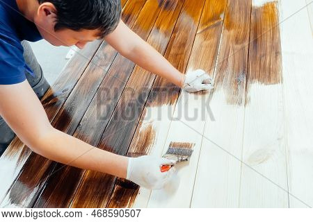 Man Paints Wooden Boards With Paint Brush. Carpenter Cabinetmaker Varnishes Wooden Surface. Authenti