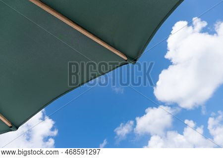 Part Of A Green Umbrella In The Foreground, With A Partly Cloudy Sky In The Background In The Caribb