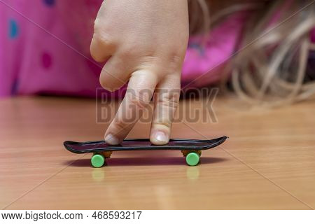 Child\'s Fingers On A Fingerboard, Wooden Surface, Close-up, Selective Focus. Fingerskate Finger Tra