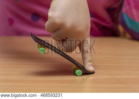 A Child\'s Hand Does A Fingerskate Trick On A Wooden Table, Close-up, Selective Focus.finger Trainin