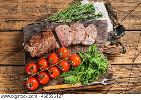 Roast Veal Tenderloin, Sliced Roastbeef On Wooden Board With Garnish. Wooden Background. Top View.