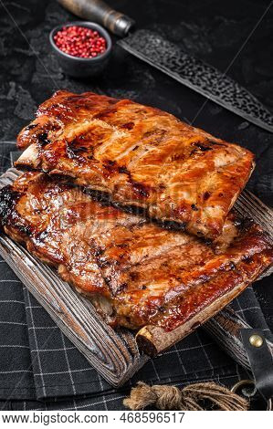 Stack Of Grilled Pork Ribs In Bbq Sauce On A Chopping Board. Black Background. Top View.