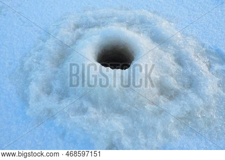 Winter Fishing In January. A Round Hole In The Ice And Snow, Made With An Ice Pick. Hobby, Sports Or