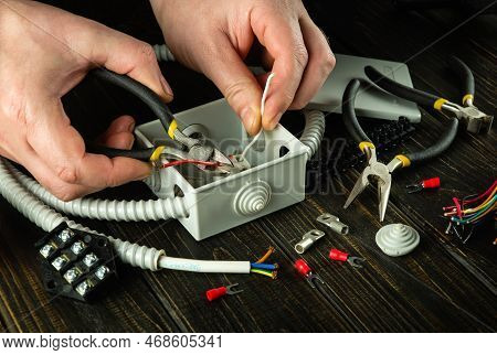 Cutting A Wire In A Gray Junction Box With Diagonal Pliers. Electrical Connection In The Workshop Of