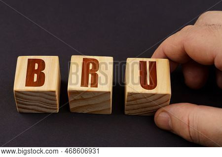 Business Concept. On A Black Surface, A Man Puts Cubes With The Inscription - Bru