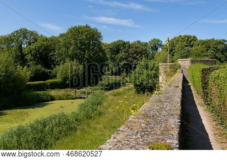 An Old Stone Wall Next To A Park With A Pond, Summer, Blue Sky, Bergues (france)