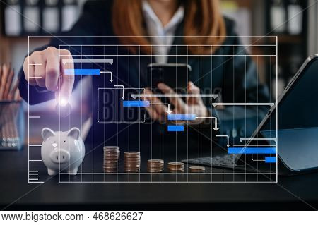Businesswoman Holding Coins Putting In Glass With Using Smartphone Ainto Piggy Bank To Calculate  Co