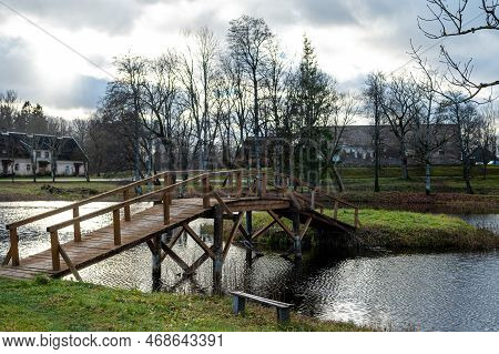 A Wooden Bridge From The Shore To A Small Island In The Lake In The Manor Park, Garsene, Latvia