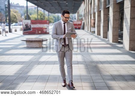 Businessman Walking On The Street And Using Tablet To Comfirm Meeting.