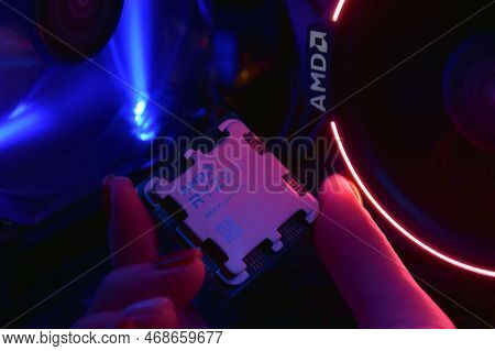 Close-up Of An Amd Ryzen 9 3900X Processor, Against The Backdrop Of Coolers With Light.