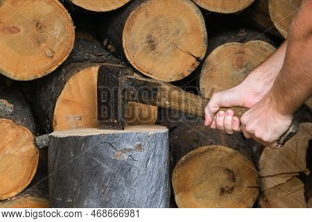 A Man Is Chopping Logs With An Axe On Chopping Block. Harvesting Of Firewood Stocks For Heating. An 