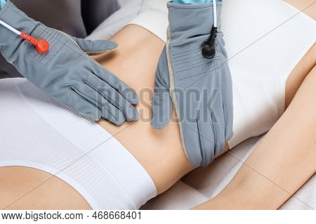 Doctor Cosmetologist Makes A Microcurrent Massage Procedure On The Belly Of A Beautiful Girl In A Be