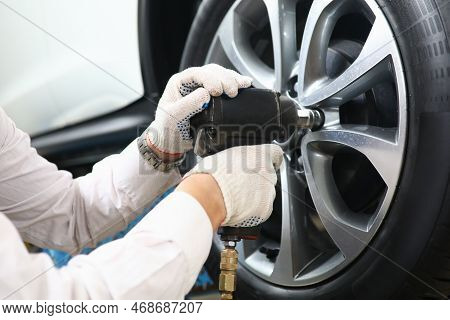 Garage Master Unscrews Nuts To Broken Wheel Of Car. Tire Service And Auto Service Concept