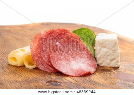 Feta und Ementhal Käse mit Salami und Gurken auf einer Holzplatte