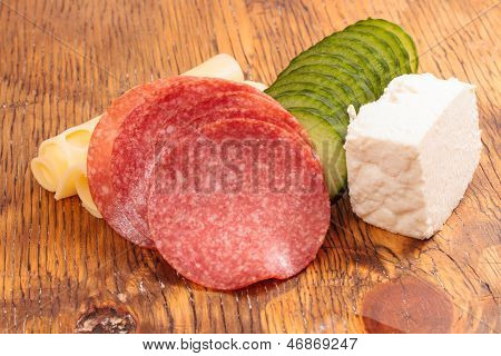Feta und Ementhal Käse mit Salami und Gurken auf einer Holzplatte