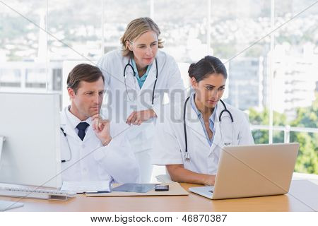Medizinisches Personal, die zusammen an einem Laptop und einem Computer in ihrem Büro arbeiten