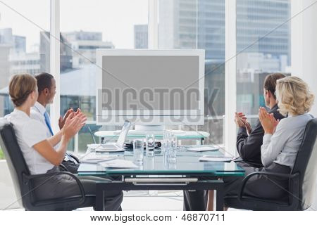 Mensen uit het bedrijfsleven applaudisseren op een scherm tijdens een videoconferentie