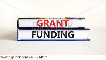 Grant Funding Symbol. Concept Words Grant Funding On Books. Beautiful White Table White Background. 