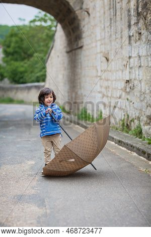 Little Handsome Baby Boy Playing With Umbrella Outdoor In Old Town. Boy Wearing Blue Jacket