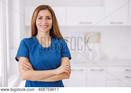 Portrait Of Young Female Doctor Wearing Uniform Standing In Er And Smiling With Hands Crossed