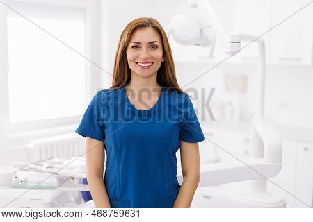 Portrait Of Female Dentist Wearing Uniform Standing Dental Clinic And Smiling