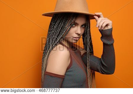 Beautiful Woman With Long African Braids And Hat On Orange Background, Space For Text